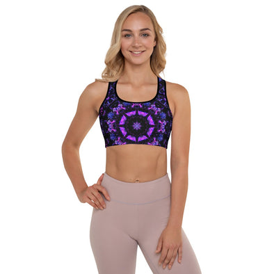 Photograph of a model wearing Bleace MetaParty Vibes Kaleidoscopic purple, blue, and pink, Trippy Visual sports bra in the foreground with a white background.  